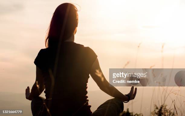 silhouette of young woman practicing yoga outdoors - zen stock pictures, royalty-free photos & images