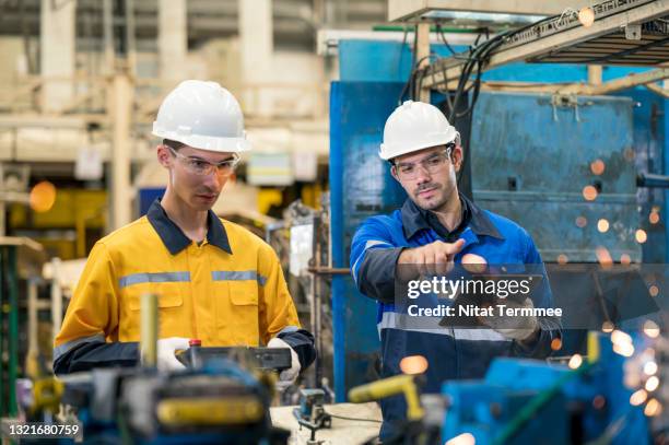 accuracy and quality control in assembly welding processes. production line surveyor engineer explaining of working standard to technician operator trainee to control automated robots welding for auto part production. - trainee program stock pictures, royalty-free photos & images