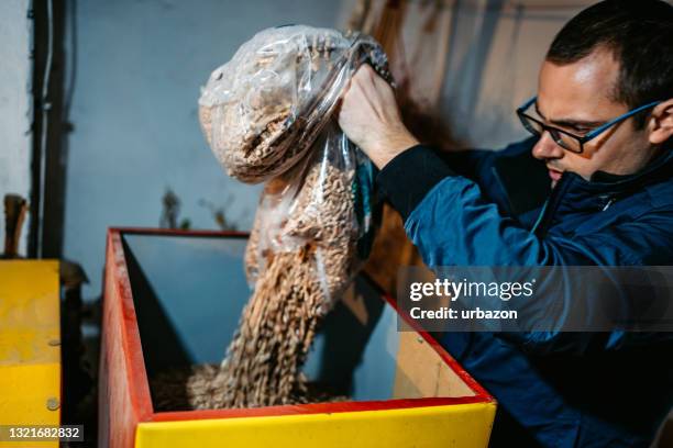 man pouring pellets in pellets boiler - biomass renewable energy source stock pictures, royalty-free photos & images