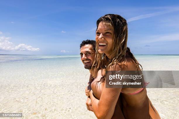 coppia felice che si diverte mentre fa il piggybacking sulla spiaggia. - zanzibar foto e immagini stock