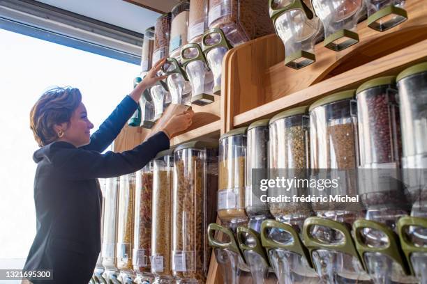 een zeer jonge vrouw gebruikt een bulkvoedseldispenser - eerlijke handel stockfoto's en -beelden