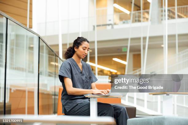 female nurse working on laptop at table in hospital - étudiant en médecine photos et images de collection