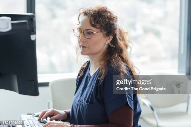 female nurse working on computer in hospital - female nurse stock-fotos und bilder