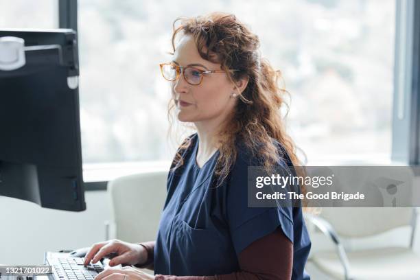 female nurse working on computer in hospital - clinical expertise stock pictures, royalty-free photos & images