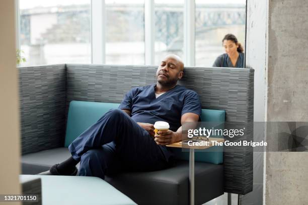 male nurse resting on sofa in hospital lounge - nurse resting stock pictures, royalty-free photos & images