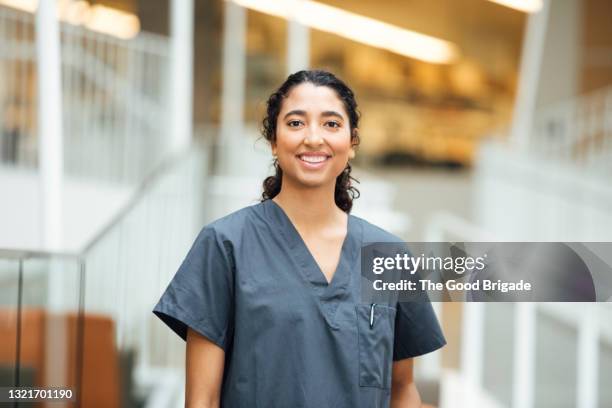 portrait of smiling nurse standing in hospital - krankenpflegepersonal stock-fotos und bilder