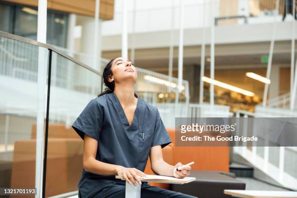 tired nurse with note pad at table in hospital - form filling stock pictures, royalty-free photos & images