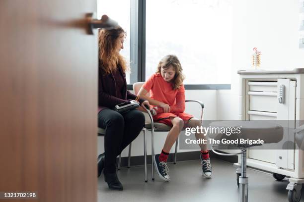 single mother talking to daughter while sitting in hospital - armbruch stock-fotos und bilder