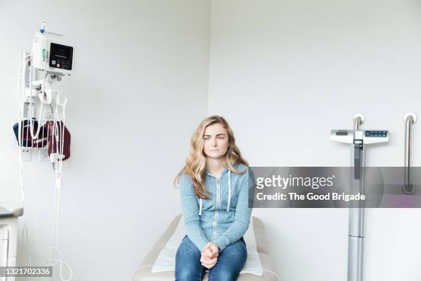 portrait of female teenager waiting in hospital exam room - girl in hospital bed sick stock pictures, royalty-free photos & images