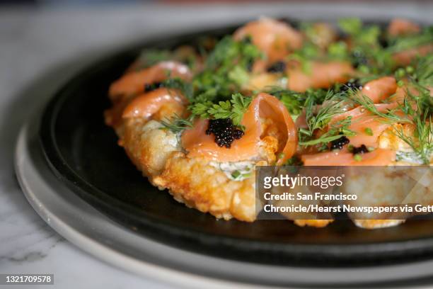 Smoked salmon, bowfin caviar, creme fraiche, and fines herbes on tater tot waffles on the menu at the Riddler on Friday, February 10 in San...