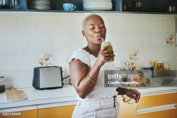 jonge afrikaanse vrouw die van een smoothie geniet die een metaalstro met behulp van - smoothie and woman stockfoto's en -beelden