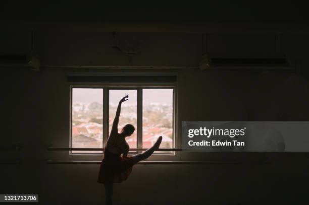 in silhouette asiatische chinesische teenager-mädchen üben ballett-tanz heben ihr bein auf barre im studio - teen girls in tights stock-fotos und bilder