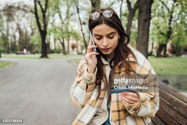 beautiful girl sitting in the park and ordering something online - spending money stock pictures, royalty-free photos & images