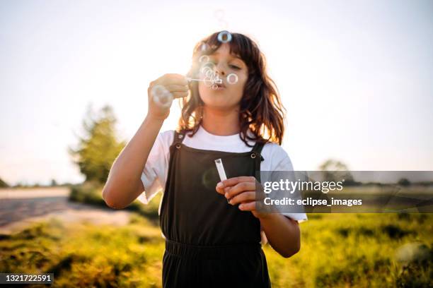 freisinnige kinder - child blowing bubbles stock-fotos und bilder