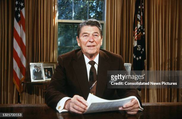 President Ronald Reagan sits behind his desk in the White House's Oval Office, Washington DC, October 14, 1987. He had just delivered an address to...