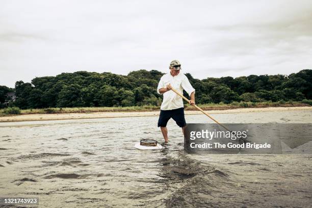 senior man digging for clams in ocean - surf casting stock pictures, royalty-free photos & images