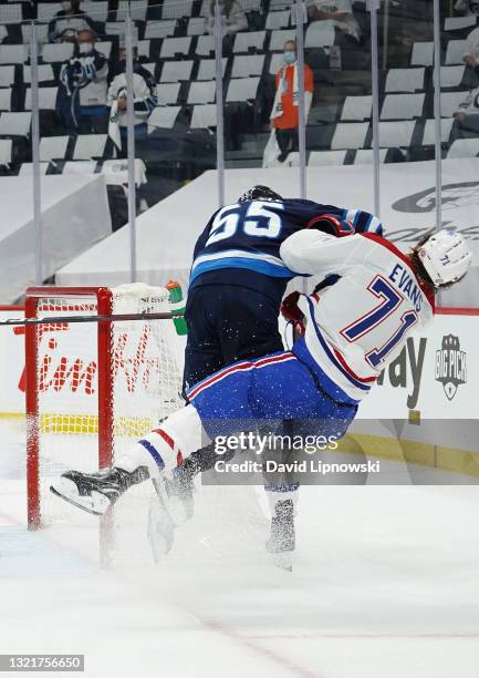 Jake Evans of the Montreal Canadiens is left injured after scoring a third period empty net goal and then checked hard by Mark Scheifele of the...