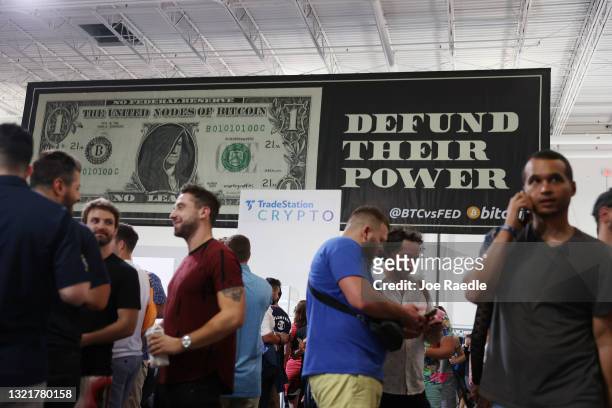 Signs hang above attendees of the Bitcoin 2021 Convention, a crypto-currency conference held at the Mana Convention Center in Wynwood on June 04,...