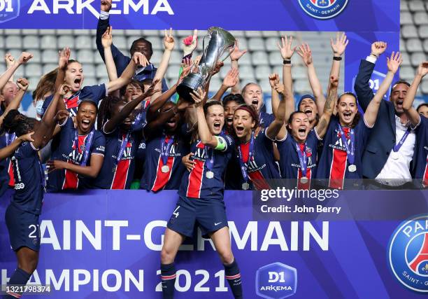 Captain Irene Paredes of PSG - holding the trophy - and teammates, far right coach of PSG Olivier Echouafni celebrate winning the 2021 French...