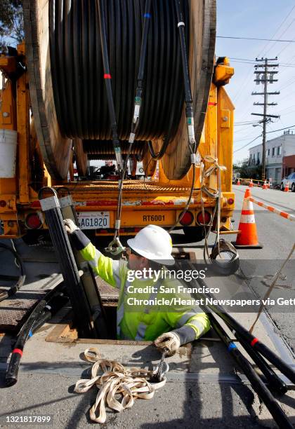 Lloyd Ratzlaff, with Pinnacle Power get set to install P.G. & E. Power lines underground through the utility vault he is climbing into along Old...