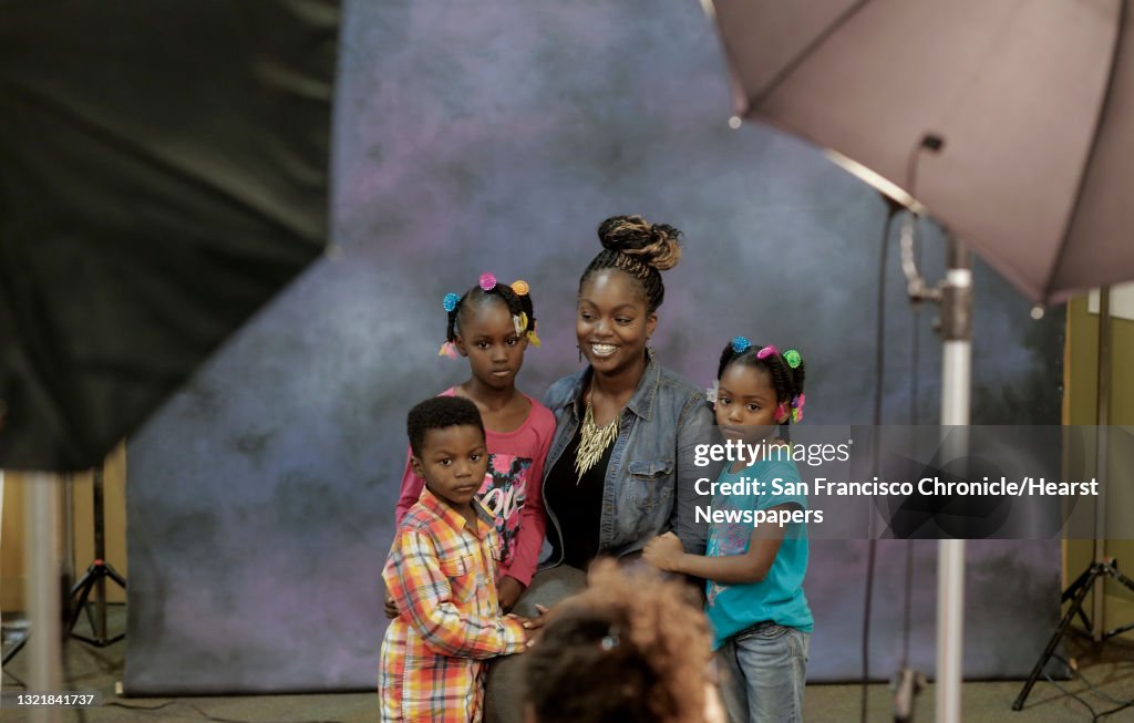 Twanisha Johnson and her children (l to r) Lamonte Kennedy,4, Leonjanae Johnson,6 and Realidy,5 have their free portraits taken during the holiday fair at Castlemont High School in Oakland, Calif. on Saturday Dec. 6, 2014.