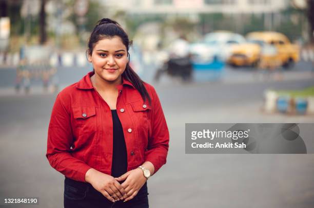 portrait of young brunette asian/ indian girl wearing red denim shirt and smiling - fat girls stock pictures, royalty-free photos & images