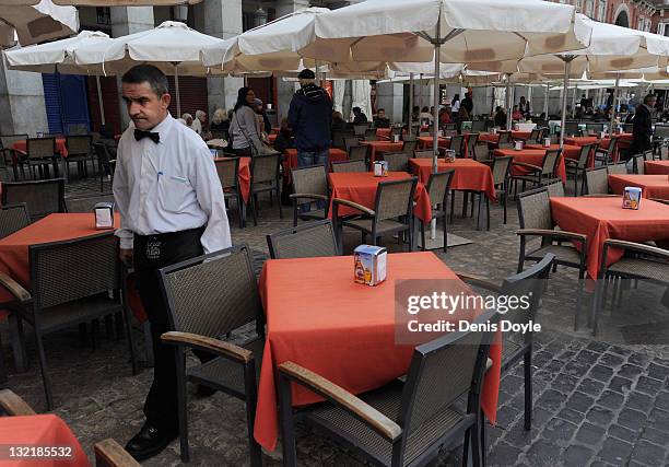 Waiter walks through empty tables as he tends to customers at a terraza in Plaza Mayor on November 9, 2011 in Madrid, Spain. The current Eurozone...
