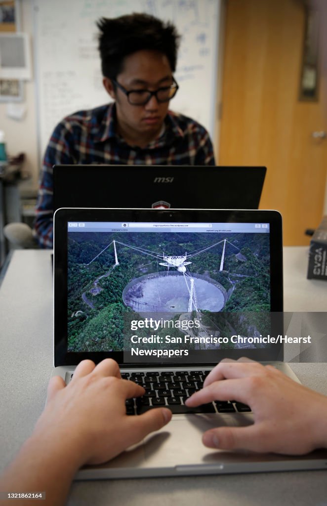 UC Berkeley student Kyle Archer, (front) studying mechanical engineering displays a photo of the Arecibo radio telescope in Puerto Rico and Kevin Leong a computer science student at work at the SETI (the Search for Extraterrestrial Intelligence) at Home