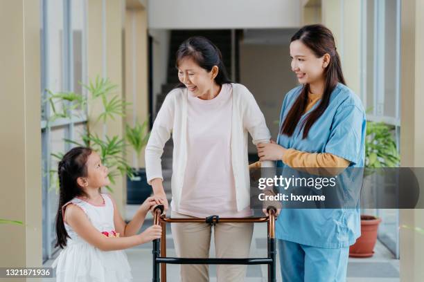 home caregiver assisting elderly woman to use walking frame - physiotherapy asian stock pictures, royalty-free photos & images