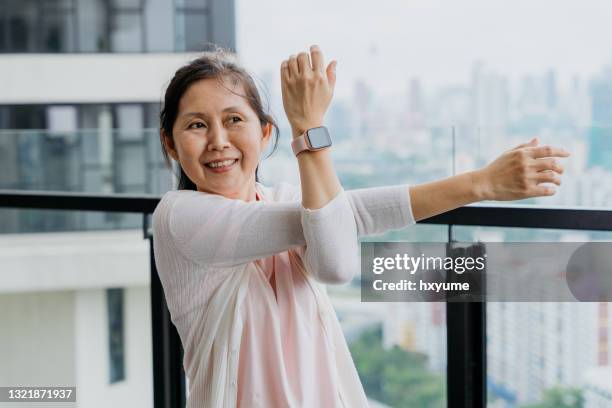 happy senior woman with smart watch doing relaxation exercise - aging happy stockfoto's en -beelden