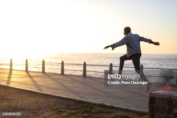 an african man taking a leap outdoors. - leap of faith stock pictures, royalty-free photos & images