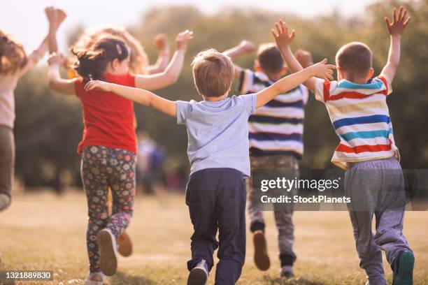 niños juguetón corriendo con los brazos levantados en un día soleado - sunny back fotografías e imágenes de stock
