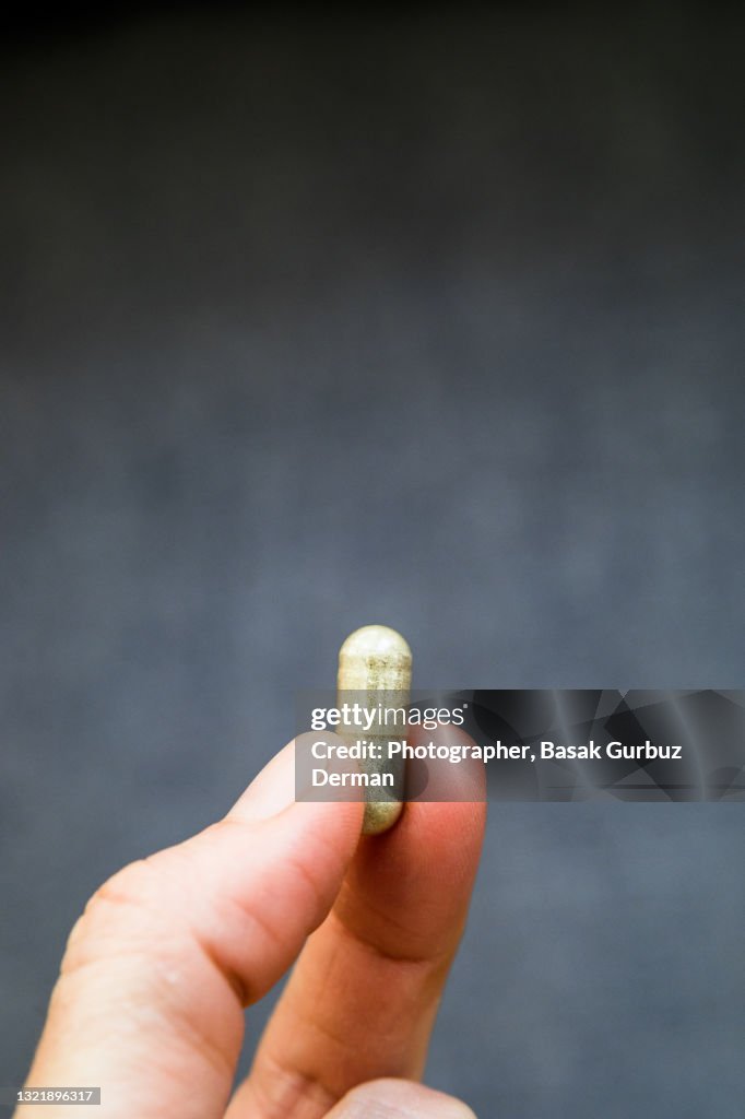 A hand holding a pill /drug / medicine