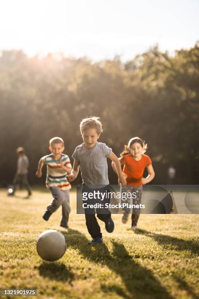bambini che giocano a calcio all'aperto - giocare foto e immagini stock