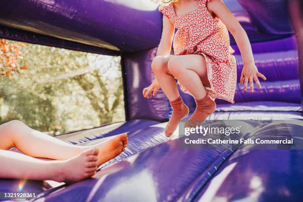 young girl bounces on a purple bouncy castle - kids feet in home stock pictures, royalty-free photos & images