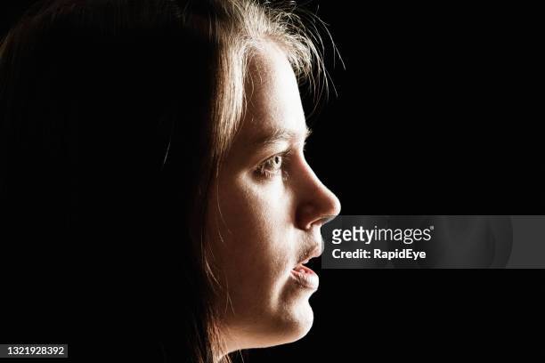 back-lit profile view of a young woman, looking haunted by uncertainty - mouth open profile stock pictures, royalty-free photos & images