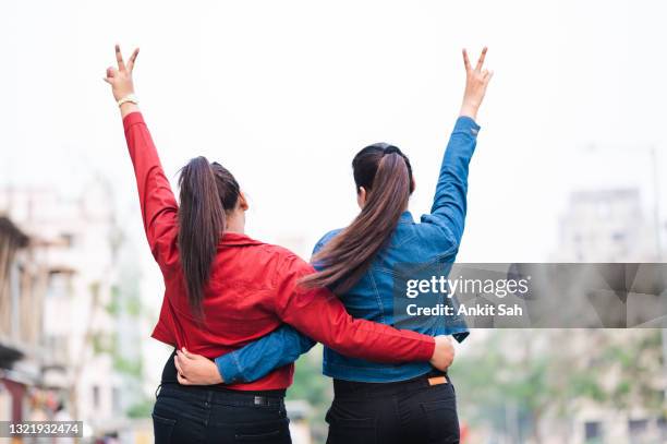 twee jonge aziatische vrouwen die pret hebben bij straat in stad- zusters die pret samen hebben. - asian twins stockfoto's en -beelden