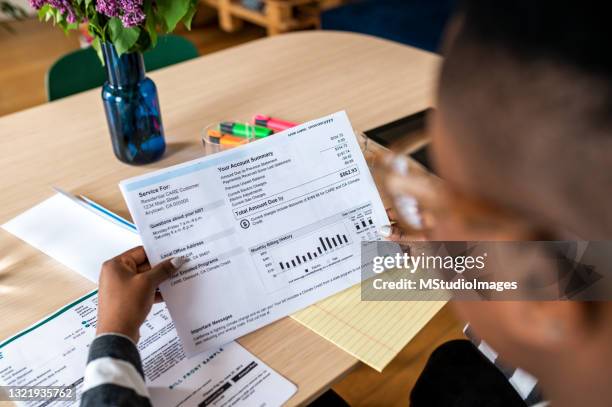 a young woman looks at the electricity bill - banking paper stock pictures, royalty-free photos & images