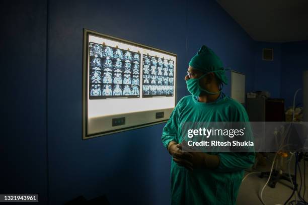 Ear, nose and throat specialist Dr. Sachin Jain checks an MRI report before performing surgery to remove mucormycosis from a patient who recovered...