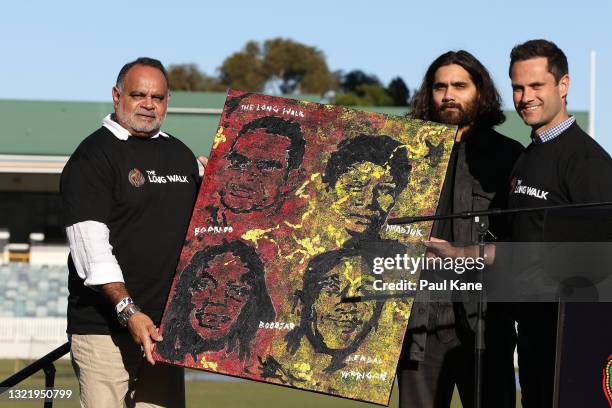 Michael Long and Gavin Wanganeen pose with artist Kambarni and his painting prior to the Long Walk from the WACA to Optus Stadium during the round 12...