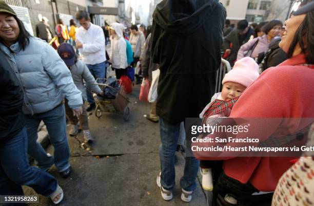 Many Zhao holds her daughter Ponnie, 9 months, as she joins hundreds lined up for grocery bags at Glide Memorials annual giveaway to needy people, on...