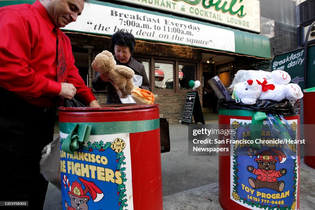 Rose Tanaka, drops off a Christmas gift to Lefty O'Doul's owner NIck Bovis during the San Francisco Firefighters last-second toy drive near Union Square, on Thursday December 24, 2009.