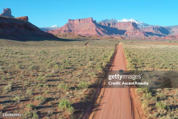 aerial view of off-road vehicle driving down desert road - desert road stock pictures, royalty-free photos & images