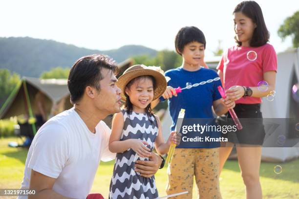 an adorable family playing with bubbles at camp ground. - part of the family stock pictures, royalty-free photos & images