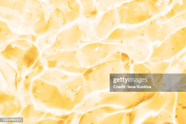 transparent yellow smudged of liquid moisture serum for face. hydrating hyaluronic acid. antibacterial aloe vera gel with bubbles. cosmetic products for skincare. cosmetology. - orange creme stock pictures, royalty-free photos & images