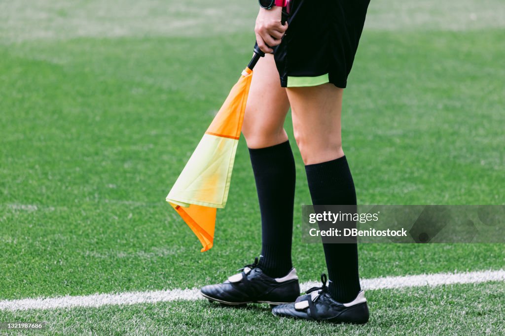 Soccer assistant linesman referee woman with the flag on the field of play, moving.
