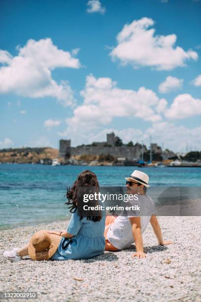lovely couple sitting on the beach, enjoying amazing moments - bodrum turkey stock pictures, royalty-free photos & images