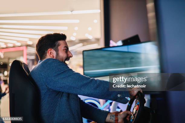 man playing a racing game in the arcade - motorsport stock pictures, royalty-free photos & images