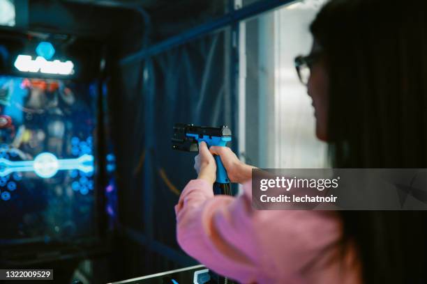 woman playing a shooter game in the arcade - target sport stock pictures, royalty-free photos & images