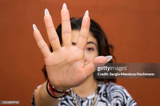 young latino woman looking at the camera and gesturing to stop, red background - 性的虐待 ストックフォトと画像